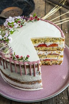 a cake with white frosting and pink icing on a plate next to some flowers