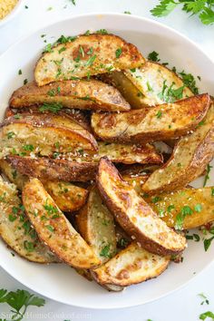 baked potato wedges in a white bowl with parsley on top