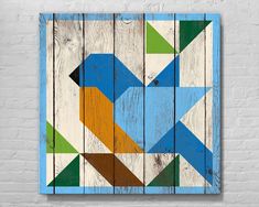 a wooden wall hanging on the side of a brick building with colorful geometric shapes painted on it