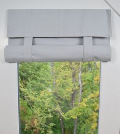 an open window with the curtains pulled back to let in light and shade on the trees outside