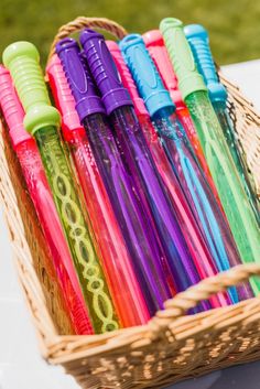 a basket filled with lots of different colored pens on top of a white tablecloth