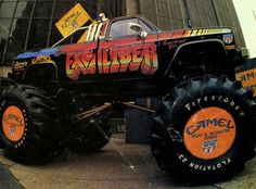 a large monster truck parked in front of a tall building