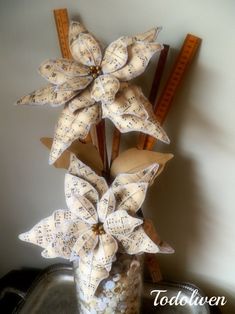 a vase filled with paper flowers and music notes on top of a metal tray next to a ruler