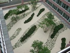 an aerial view of a courtyard with trees and rocks on the ground in front of a building