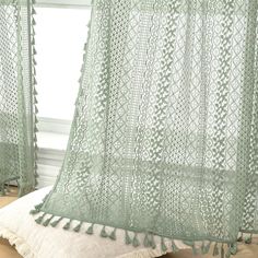 a green crocheted curtain with tassels hanging from it's side