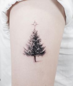 a small pine tree tattoo on the right side of the thigh, with a star above it