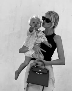 a woman holding a baby in her arms and a handbag on the other side