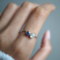 a woman's hand with a diamond and blue sapphire ring on her finger,