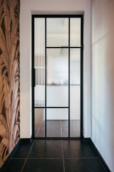 an open door leading into a room with black tile flooring and wall paper on the walls