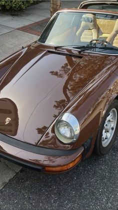 a brown sports car is parked on the street