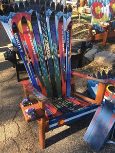 a chair made out of skis sitting on the ground next to other chairs and snowboards