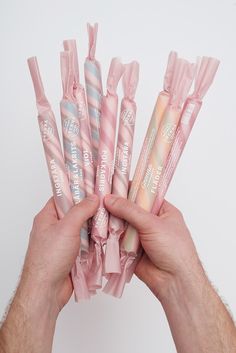 a person holding five pink and white candy bars in their hands, with the wrapper wrapped around them