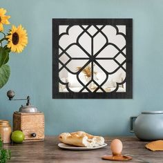 a wooden table topped with a plate of food next to a vase filled with sunflowers