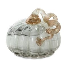 a glass pumpkin shaped object sitting on top of a white surface with gold trimmings