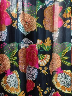 the shower curtain is decorated with colorful flowers and fish on black fabric, along with an orange butterfly