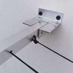 a close up of a metal object attached to a white wall with black cords on it