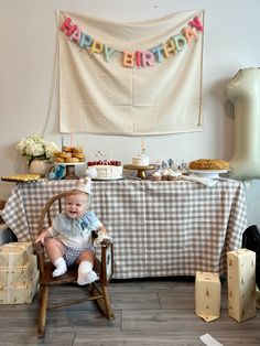 a baby sitting in a chair at a birthday party