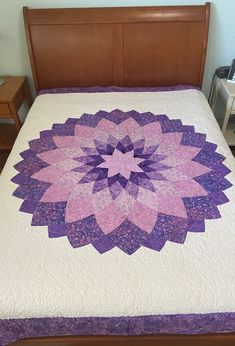 a bed with a purple and white quilt on it