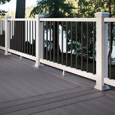 a white deck with railings and trees in the background