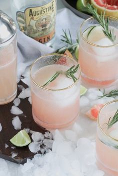 three glasses filled with pink lemonade and rosemary garnish on top of ice