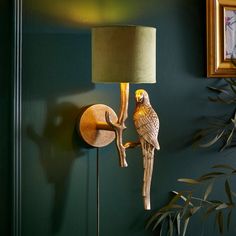 a bird is perched on the arm of a wall lamp next to a potted plant