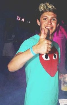 a young man is making a thumbs up sign with his hand while standing in front of other people