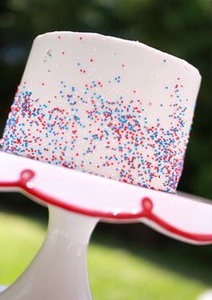 a red, white and blue cake with sprinkles sitting on a plate