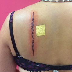 the back of a woman's shoulder with a piece of yellow paper on it