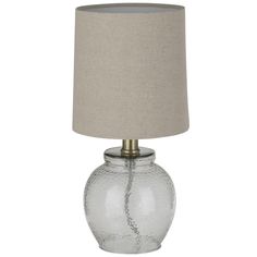 a glass table lamp with a beige shade on the base and a light grey linen shade