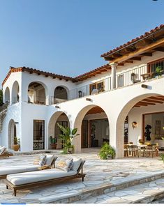 an outdoor patio with chaise lounges and potted plants in front of the house