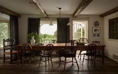 the dining room table is surrounded by wooden chairs and windows that look out onto an outdoor deck