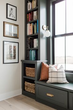 a window seat in front of a bookshelf with pictures on the wall behind it