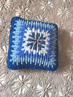 a blue and white knitted square on a doily