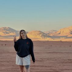 a woman is standing in the desert with her peace sign