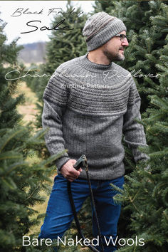 a man standing in front of a christmas tree wearing a knitted sweater and hat