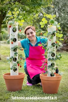 a woman kneeling next to two potted plants