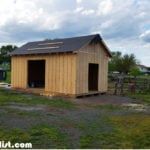 a small wooden shed sitting on top of a lush green field