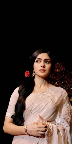 a woman with long hair wearing a white sari and red flower in her hair