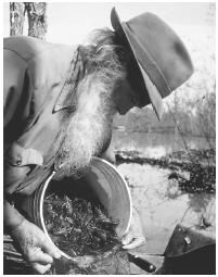 a black and white photo of a man holding a bucket with something in his hand