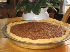 a pie sitting on top of a wooden table next to a vase with flowers in it