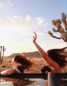 two women in the back of a pick up truck reaching for a frisbee