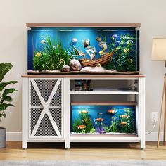 an aquarium with fish and plants in it on top of a white entertainment center cabinet