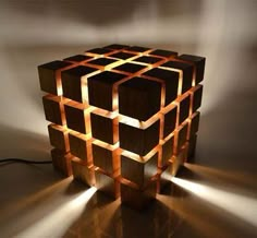 a lamp made out of wooden blocks with light coming from the top and bottom, on a table