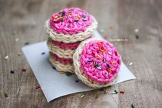 three crocheted donuts with sprinkles sitting on top of a piece of paper