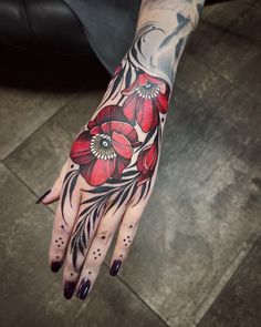 a woman's hand with red flowers on it and black dots around the wrist