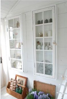 an old cabinet with glass doors is next to some flowers and other items on the table