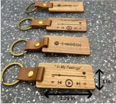 four wooden keychains with metal handles and leather straps are shown next to each other