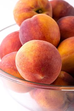 a glass bowl filled with peaches on top of a table