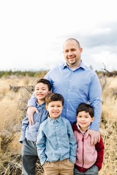 a man and two boys are standing in the grass with their arms around each other