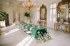 a long table is set up in the middle of a room with mirrors and chandeliers